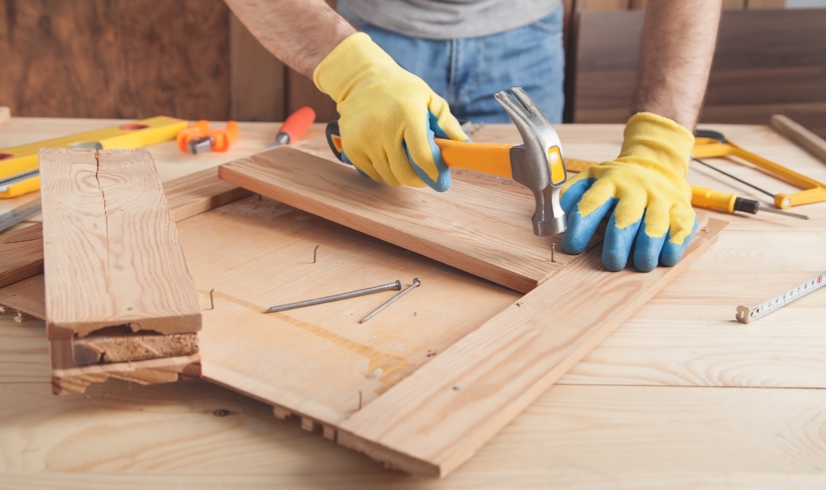 Ein Handwerker hämmert Nägel in ein Brett.