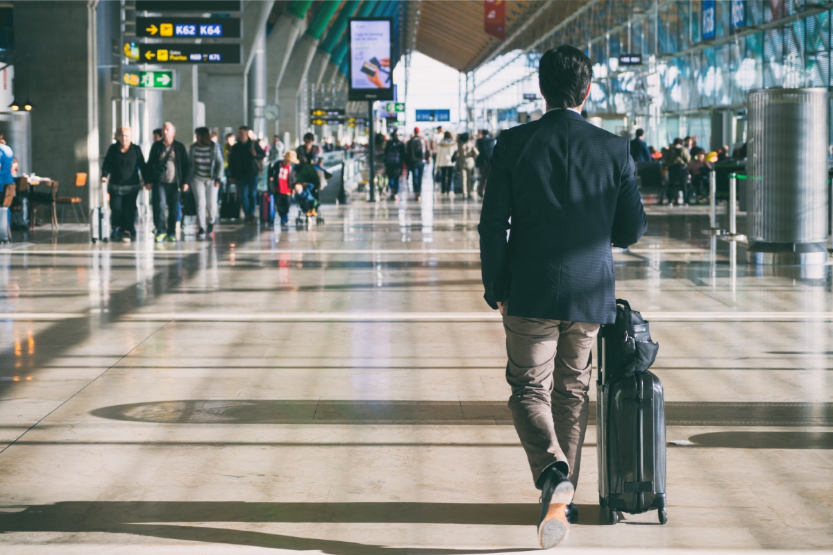 Ein Geschäftsmann mit einem Koffer an einem Flughafen.