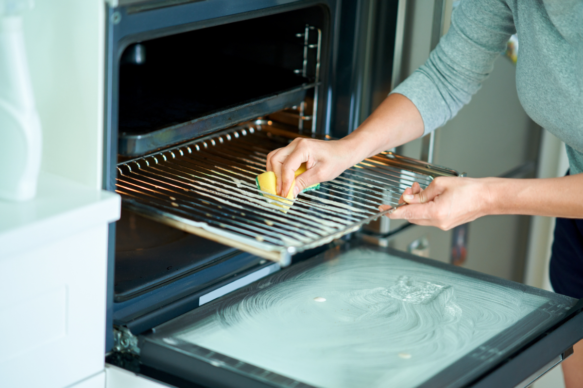 Ein Foto zeigt eine Frau beim Backofen reinigen.