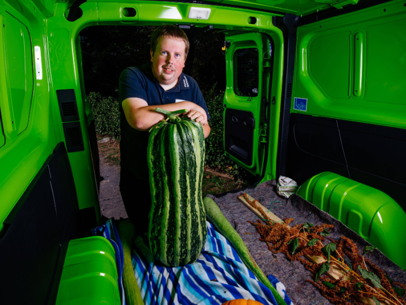 Ein Mann steht in seinem Laster und zeigt seine riesige Wassermelone.