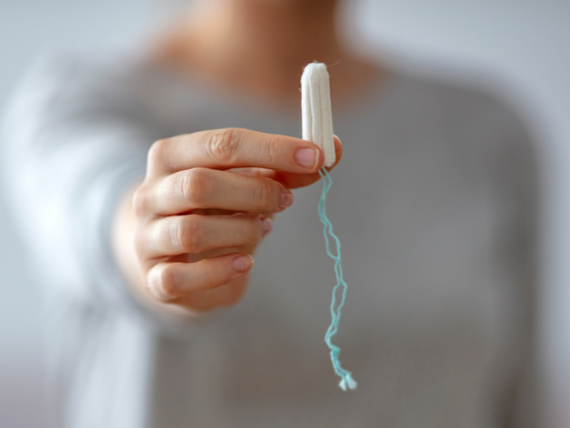 Eine Frau hält einen Tampon in die Kamera.