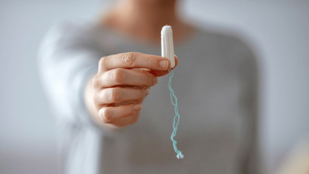 Eine Frau hält einen Tampon in die Kamera.