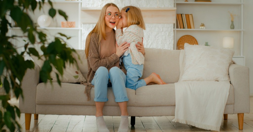 Jugendliche sitzt mit ihrer kleinen Schwester auf der Couch