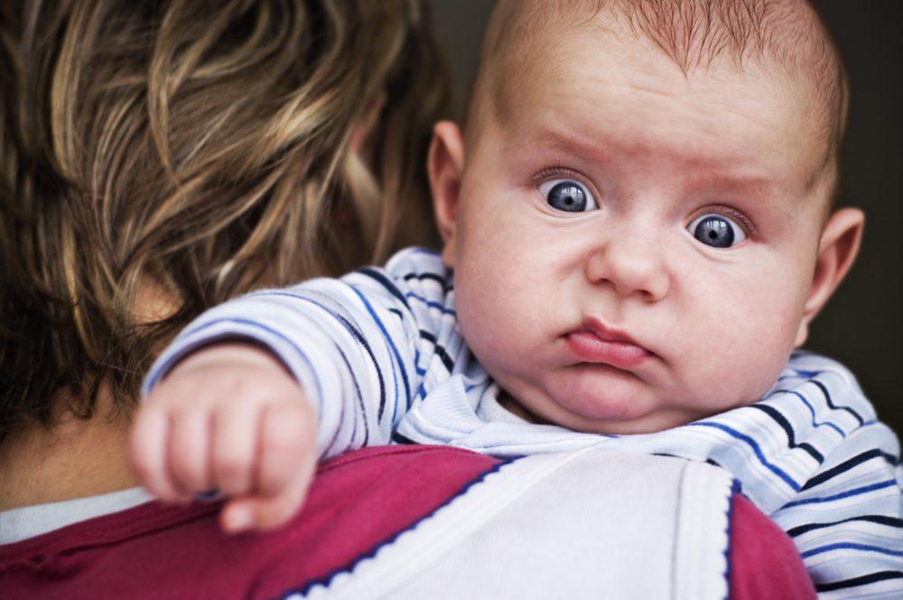 Ein Baby schaut über die Schulter seiner Mutter.