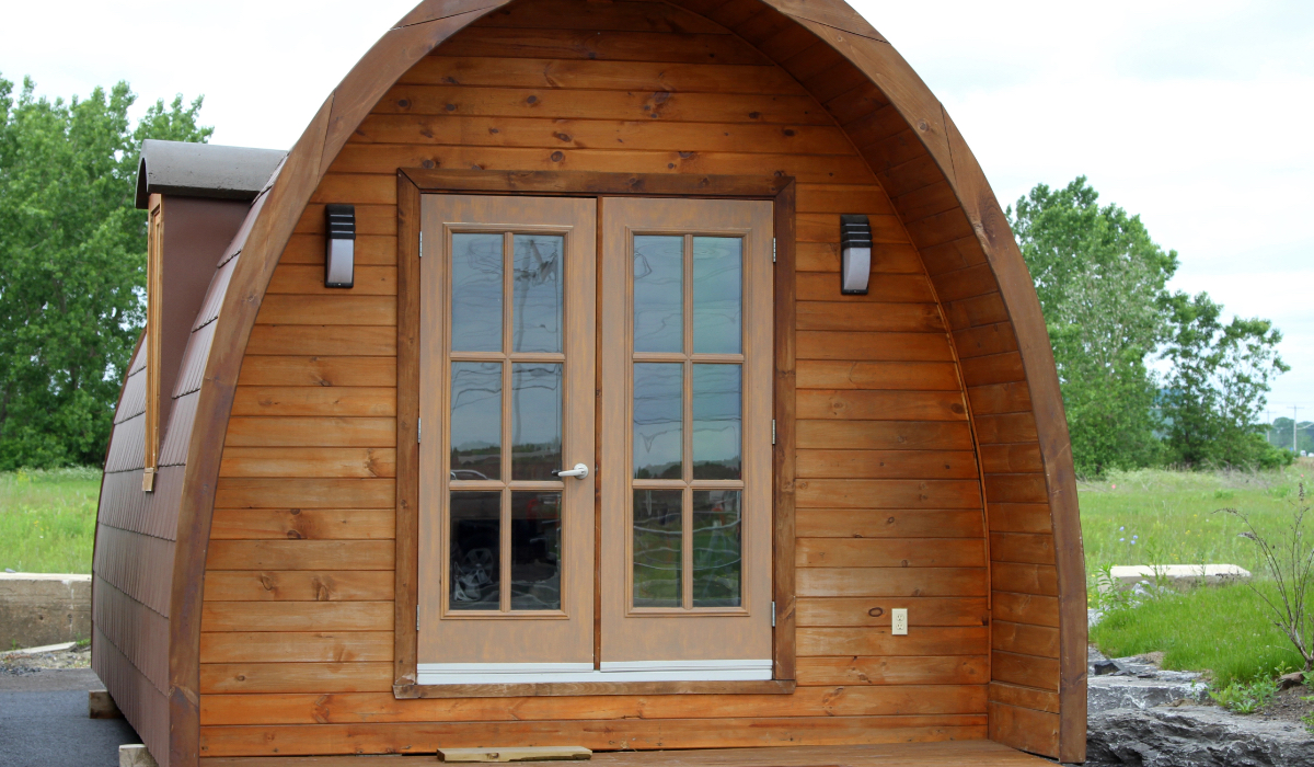 Ein Tiny House mit gewölbtem Dach in einem Garten.