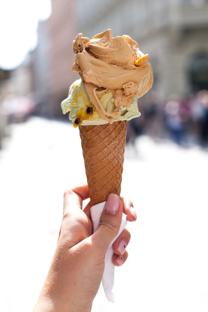 Frau hält Waffel mit zwei Kugeln Eis in der Hand.