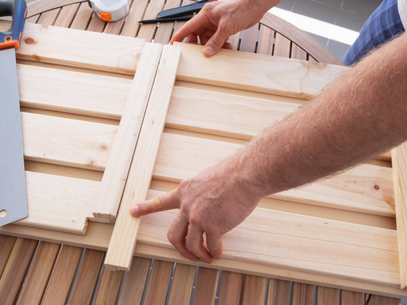 Mann baut etwas aus Holz auf einem Balkon