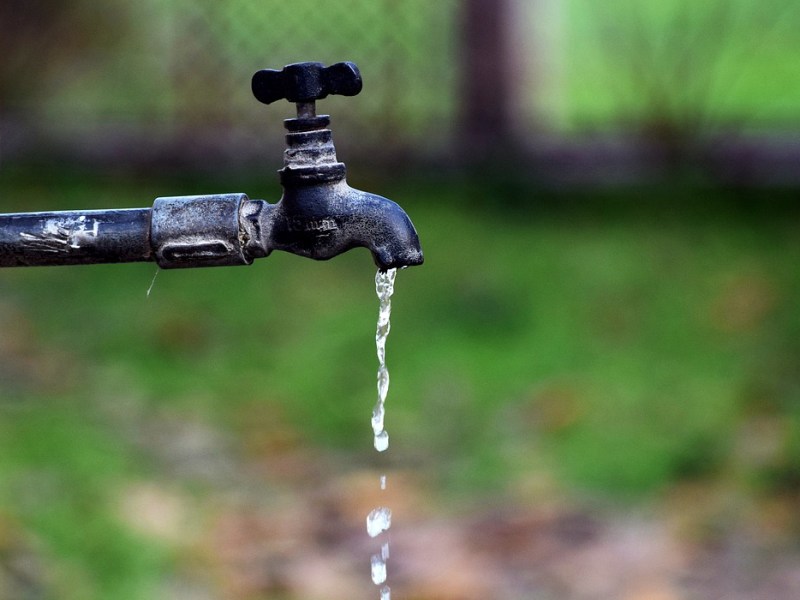 Ein tropfender Wasserhahn in einem Garten.