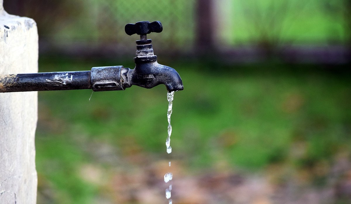 Ein tropfender Wasserhahn in einem Garten.