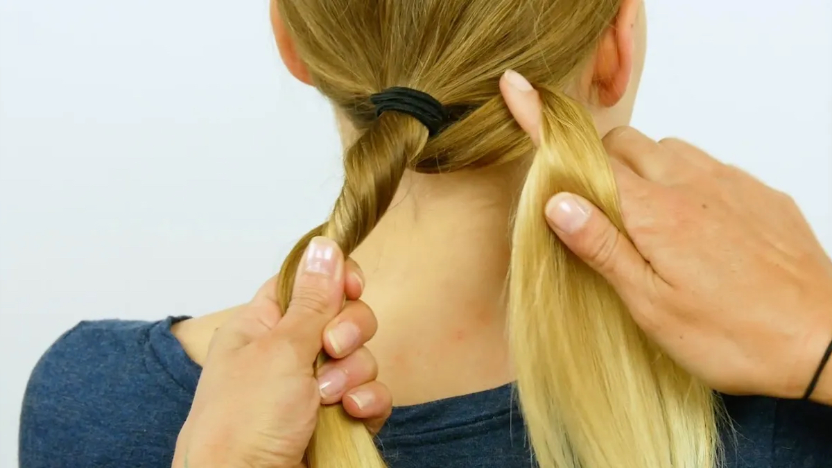 Das blonde Haar einer Frau wird um einen Finger gezwirbelt.