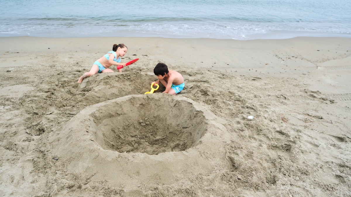 zwei Kinder bauen alleine eine große Sandburg am Strand