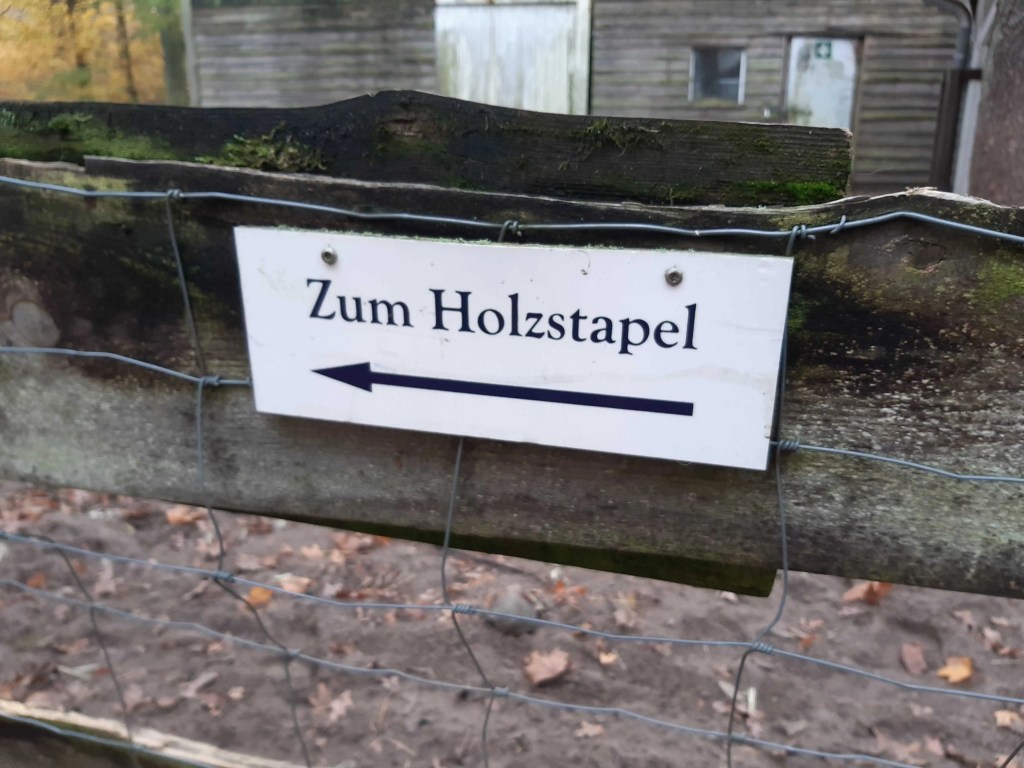 Ein Wegweiser, auf dem steht: „Zum Holzstapel“