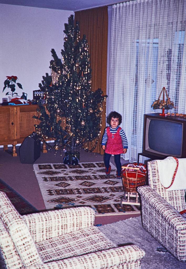 Historisches Foto zeigt Kind vor einem Weihnachtsbaum.