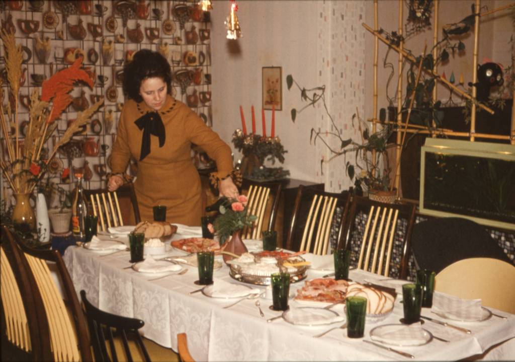 Altes Bild zeigt eine Frau, die den Tisch zum Abendbrot deckt.