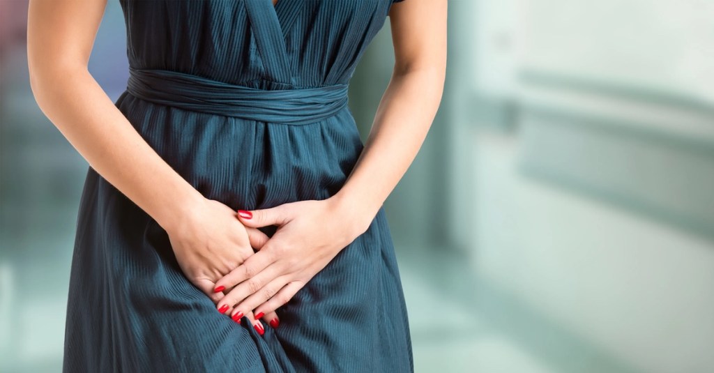 Frau hält sich die Blase und muss dringend auf die Toilette.