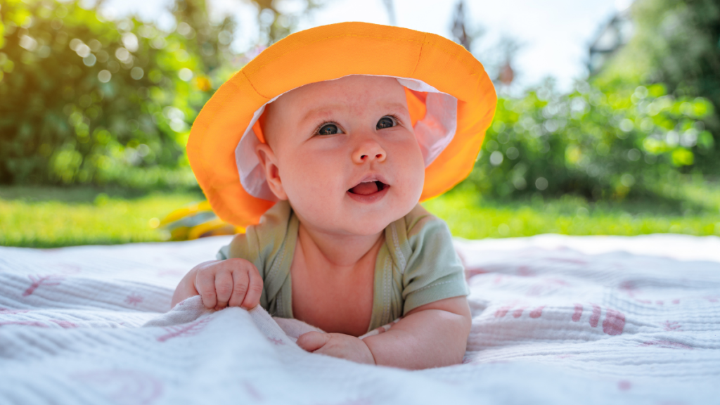 Ein Baby auf einer Decke mit gelbem Sonnenhut.