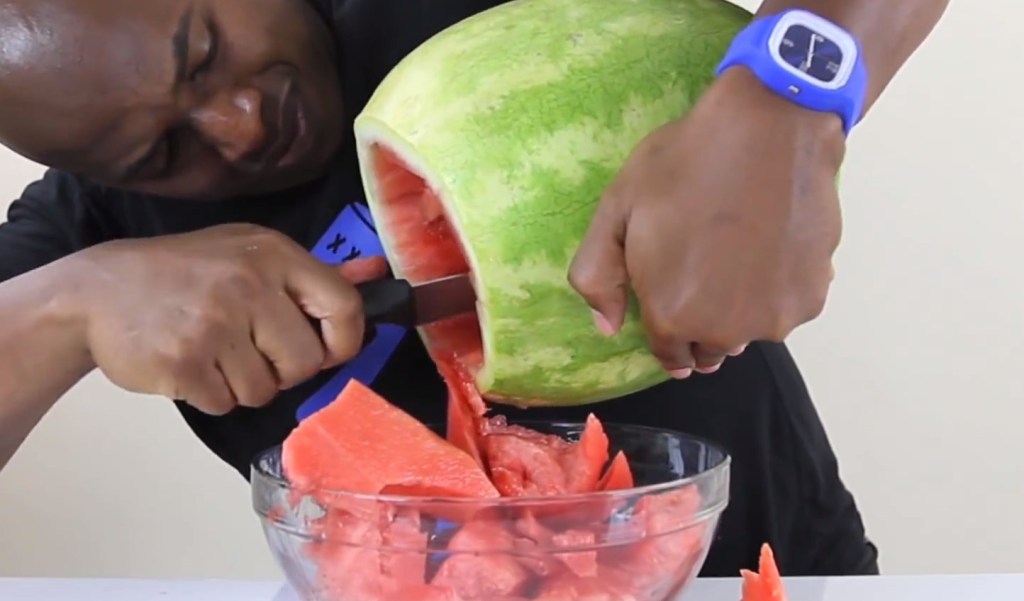 Ein Mann höhlt das Innere einer Wassermelone aus.