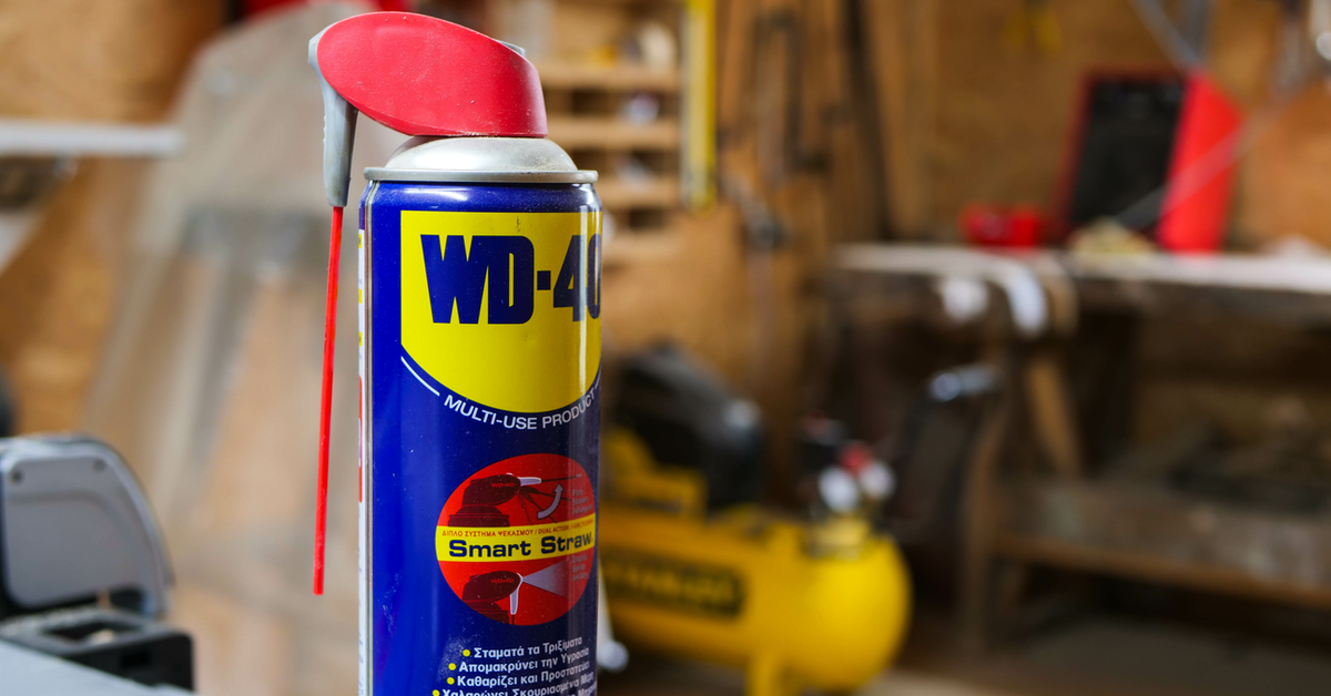 Eine Flasche WD-40 im Vordergrund. Im Hintergrund sieht man eine Werkstatt.