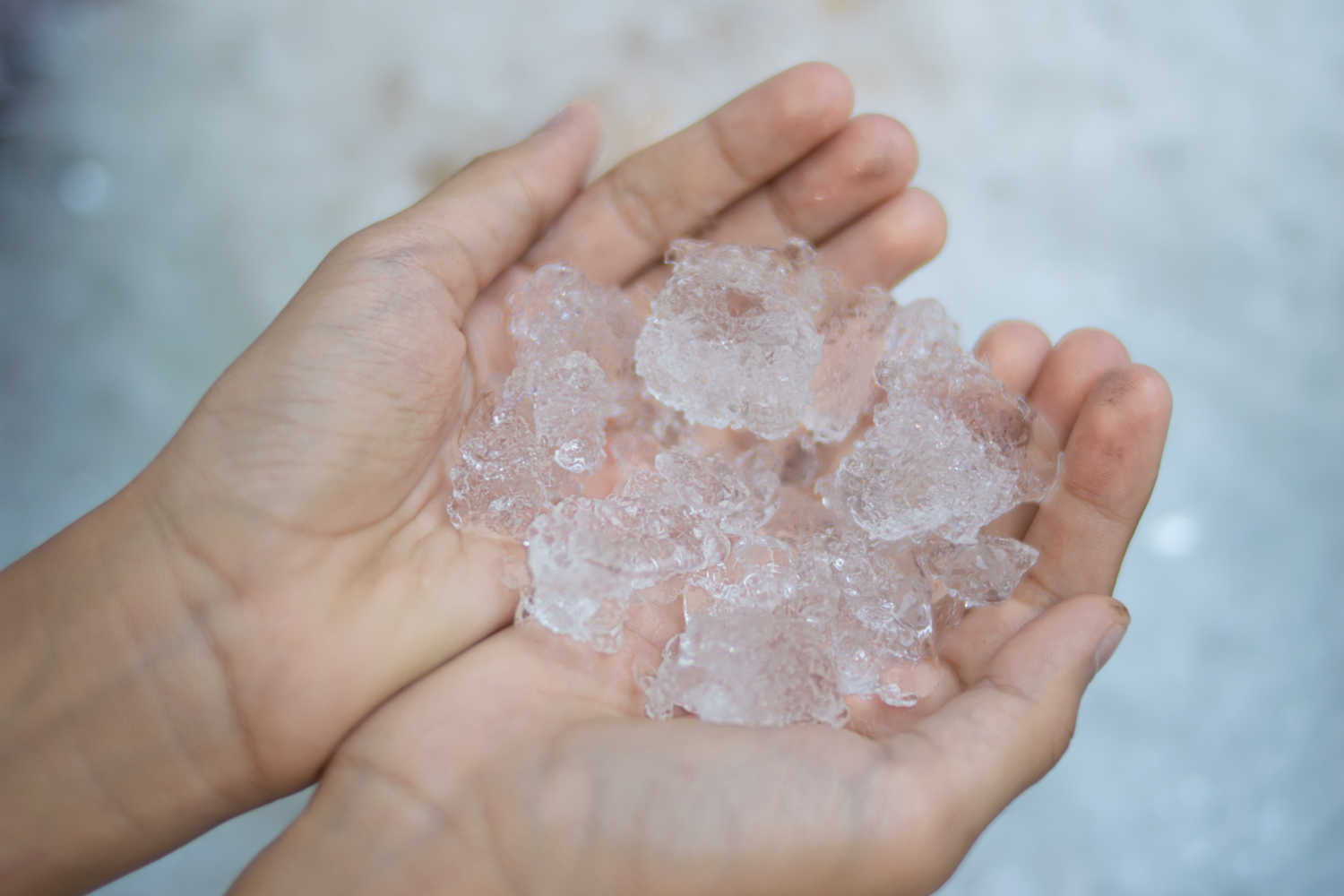 Eine Person hÃ¤lt einige unregelmÃ¤ÃŸig geformte EiswÃ¼rfel in ihren HÃ¤nden. 