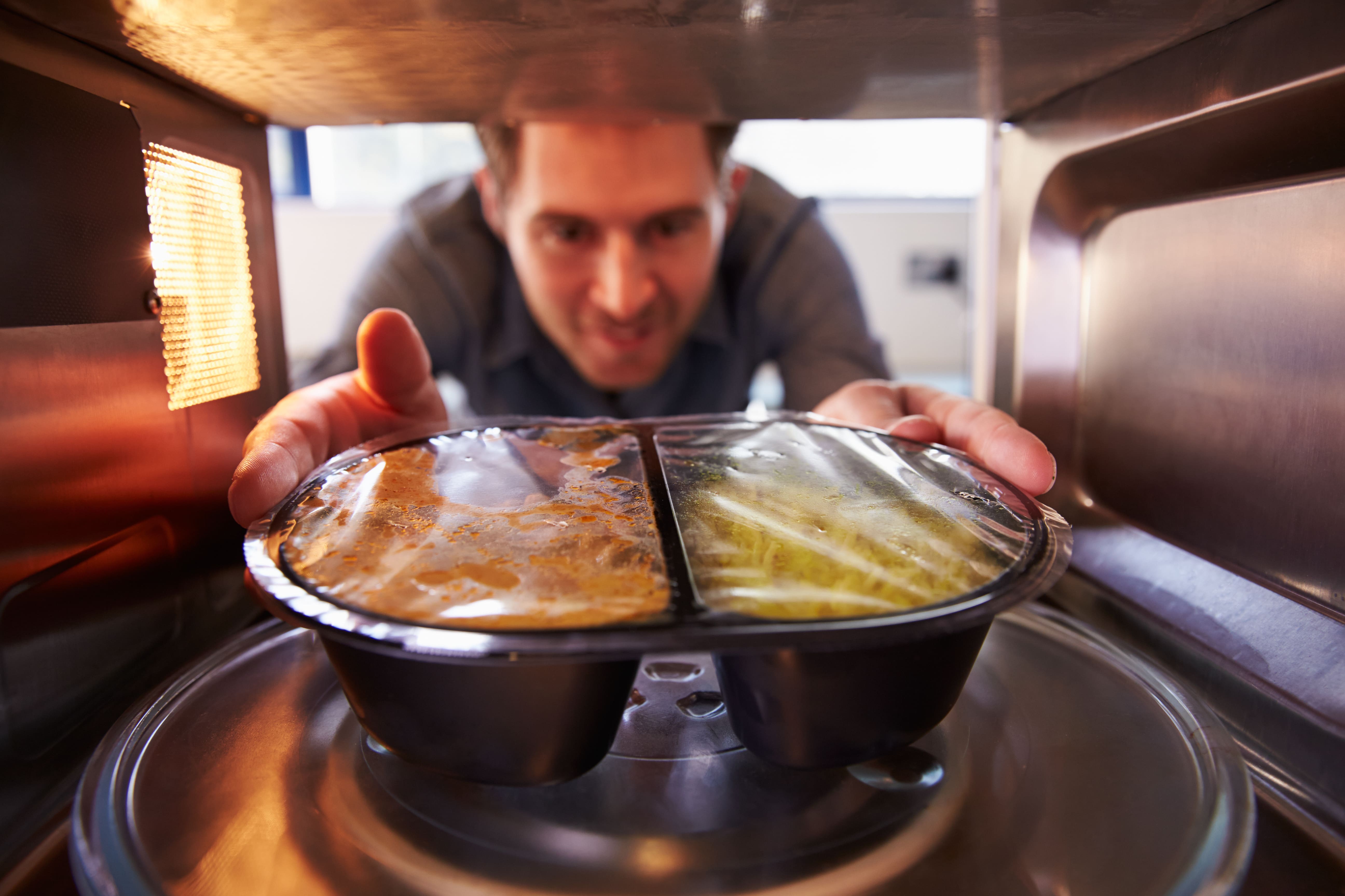 Mann holt Essen aus der Mikrowelle