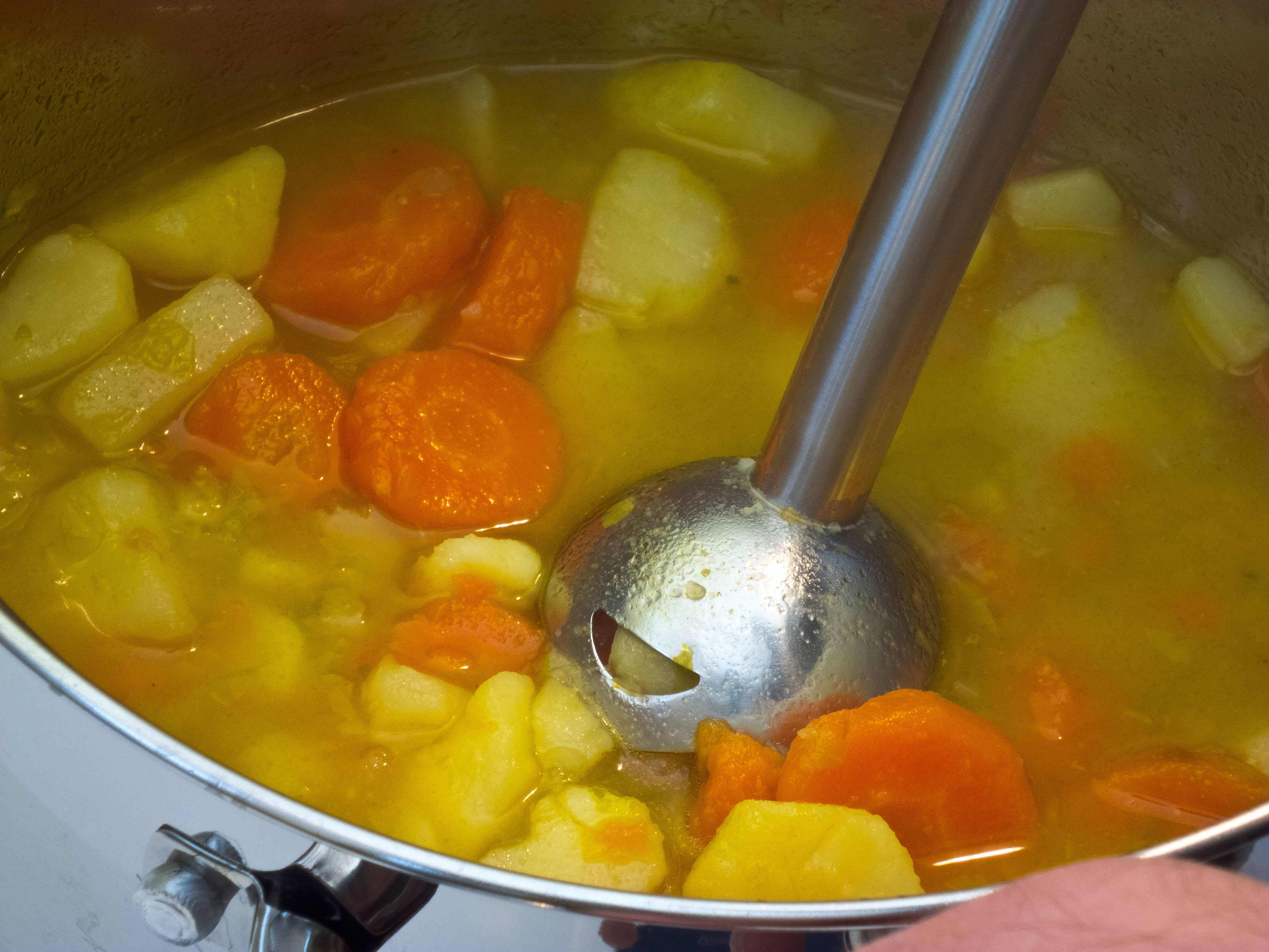 Jemand pÃ¼riert eine Kartoffelsuppe mit einem Stabmixer.