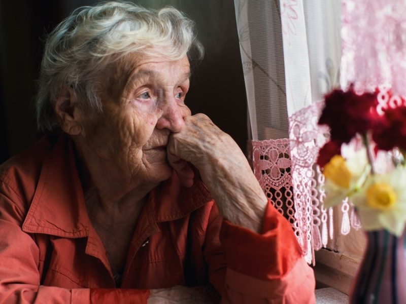 Seniorin sitzt am Fenster