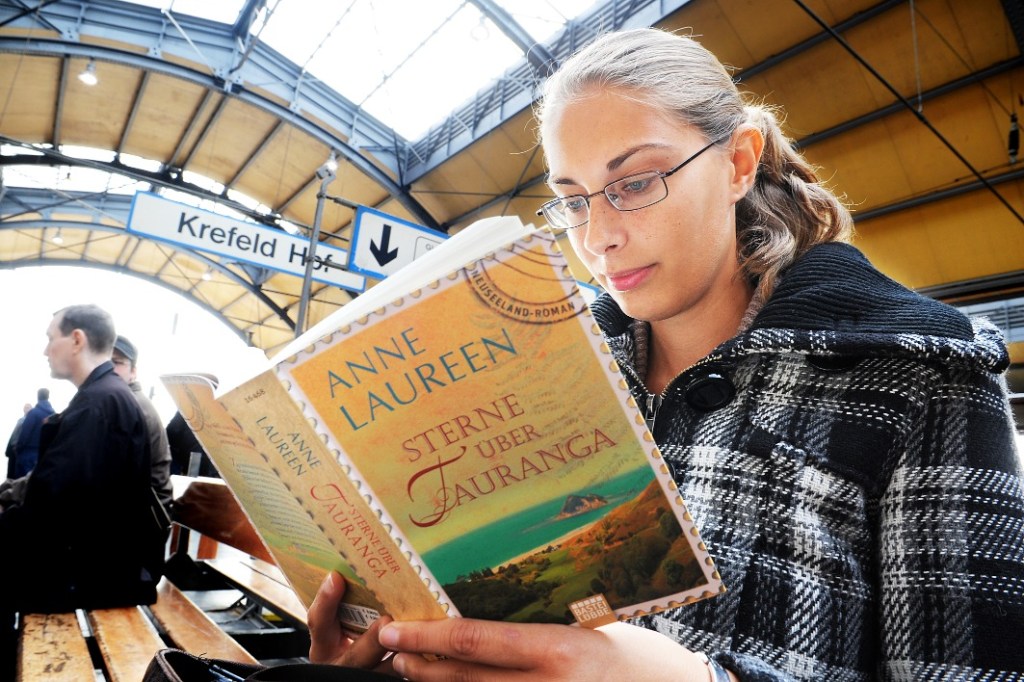 Frau liest am Bahnhof ein Buch