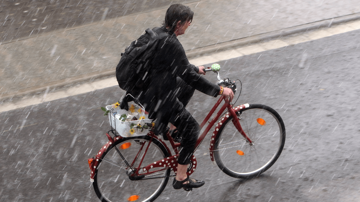 Eine Frau fährt mit ihrem Fahrrad durch den Regen.