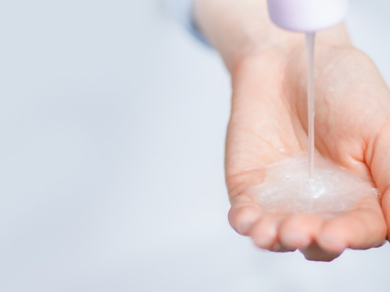 Haarshampoo wird aus der Flasche auf eine Hand gedrückt