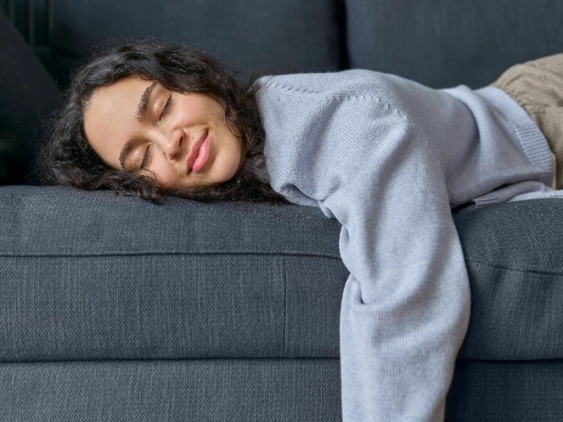 Eine Frau liegt in Bauchlage auf einem Sofa.