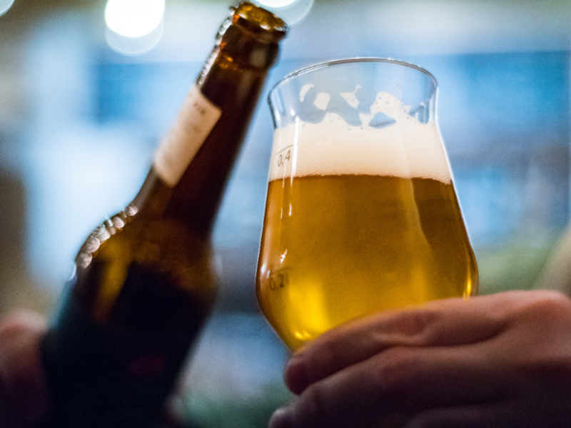 Person schenkt Bier aus Flasche in ein Glas.