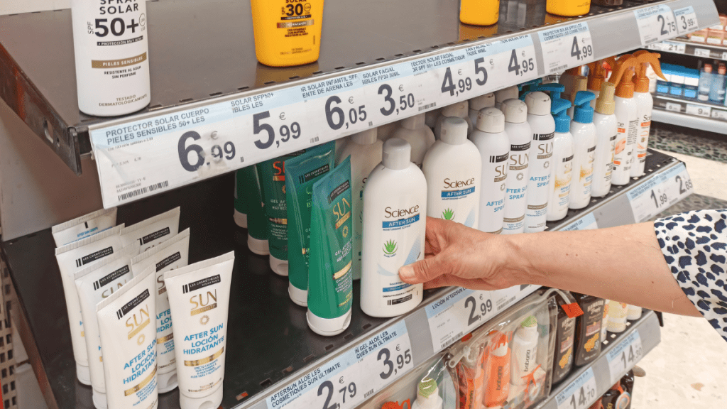 Eine Person greift im Supermarkt nach einer After-Sun-Flasche.