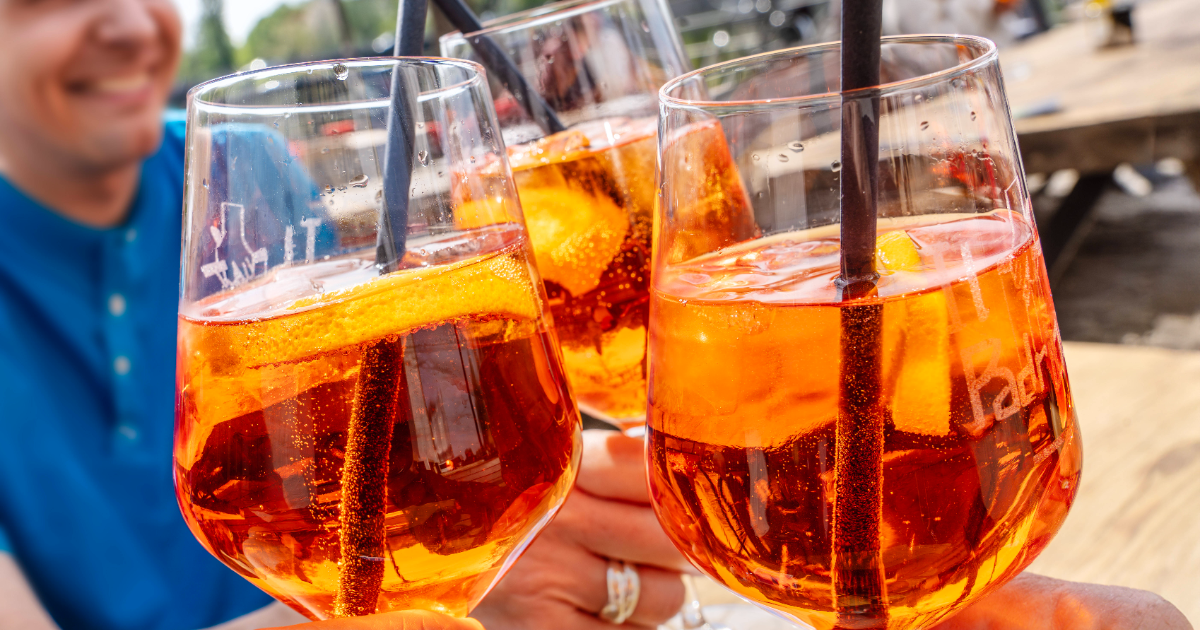 Drei Gläser mit Aperol Spritz in der Sonne.