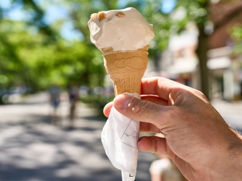 Jemand hält ein Eis in der Waffel in der Hand.