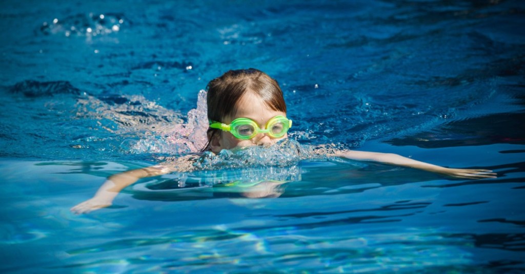 Kind mit Schwimmbrille schwimmt im Wasser