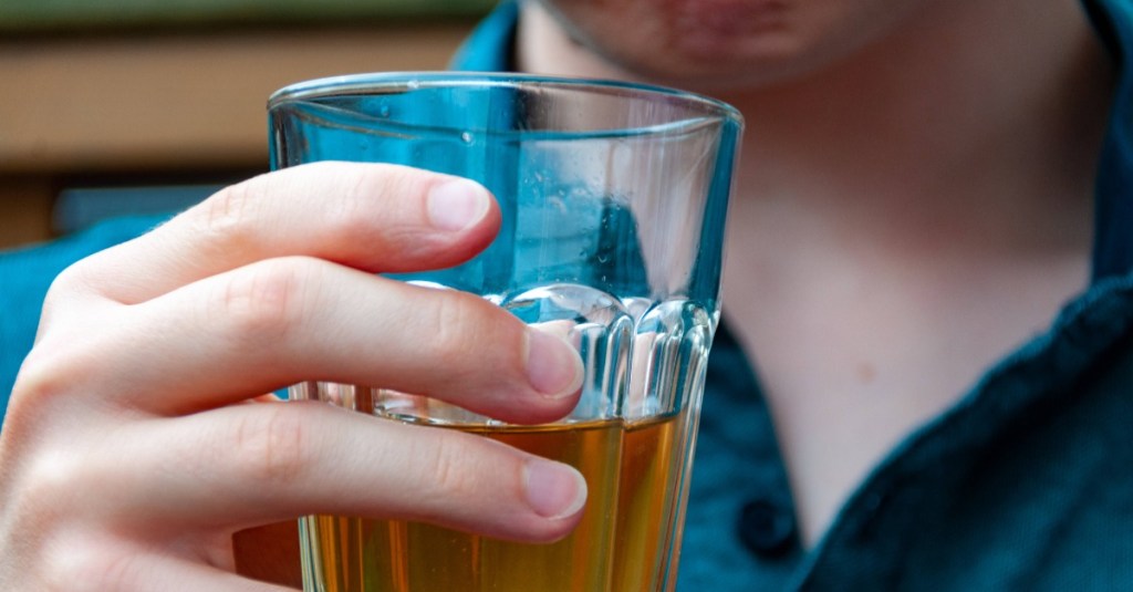 Ein Glas mit Brottrunk wird in der Hand gehalten.