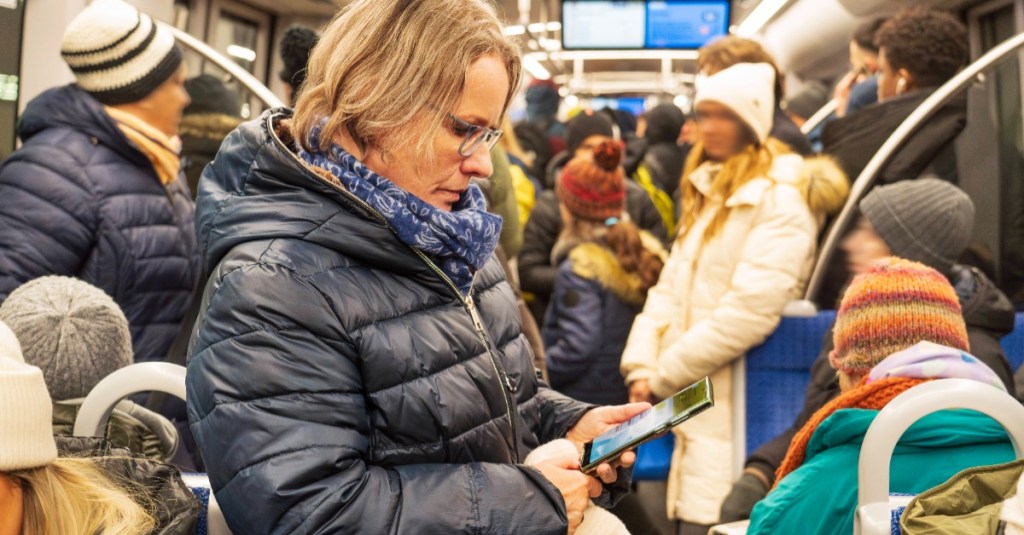 Eine Frau liest auf ihrem Smartphone in der Bahn.