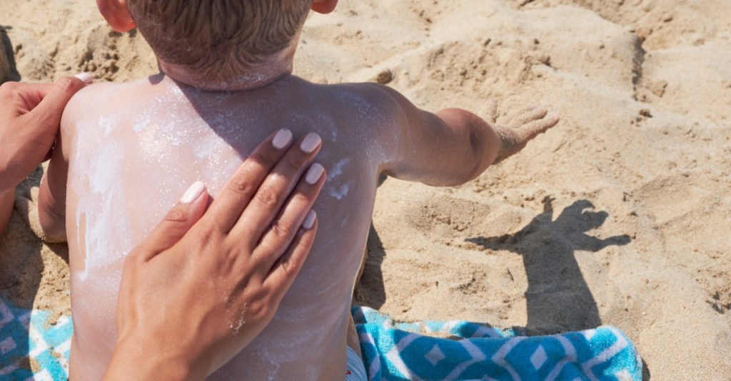 Mutter schmiert ihren Sohn mit Sonnencreme ein