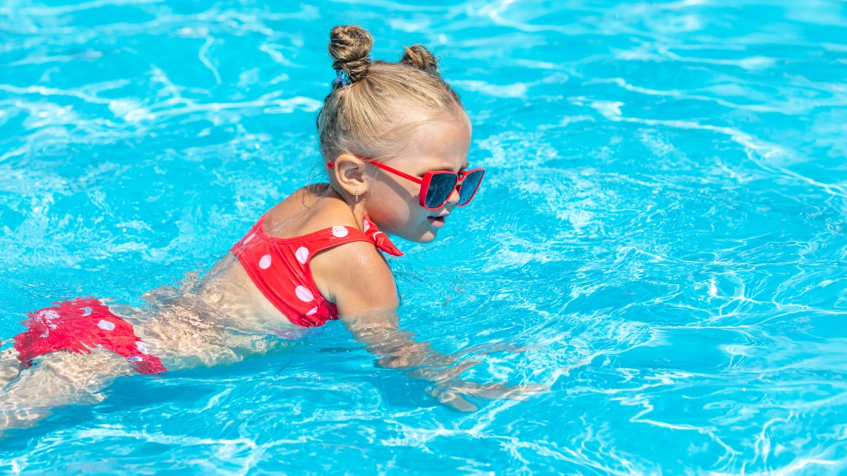 Mädchen im rosa Bikini planscht im Wasser