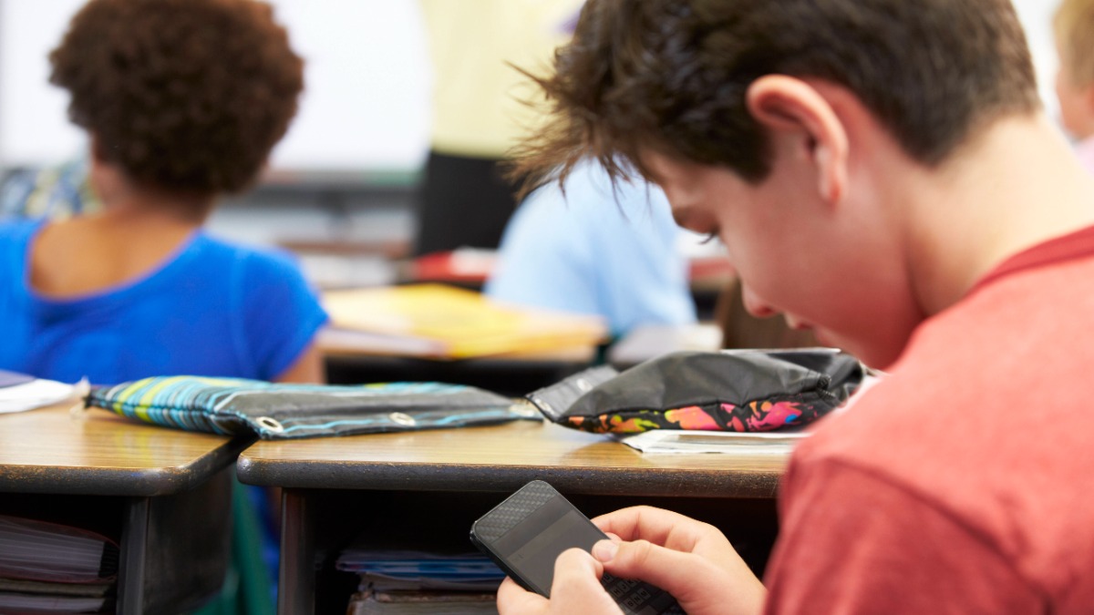 Ein Schüler benutzt ein Handy im Unterricht