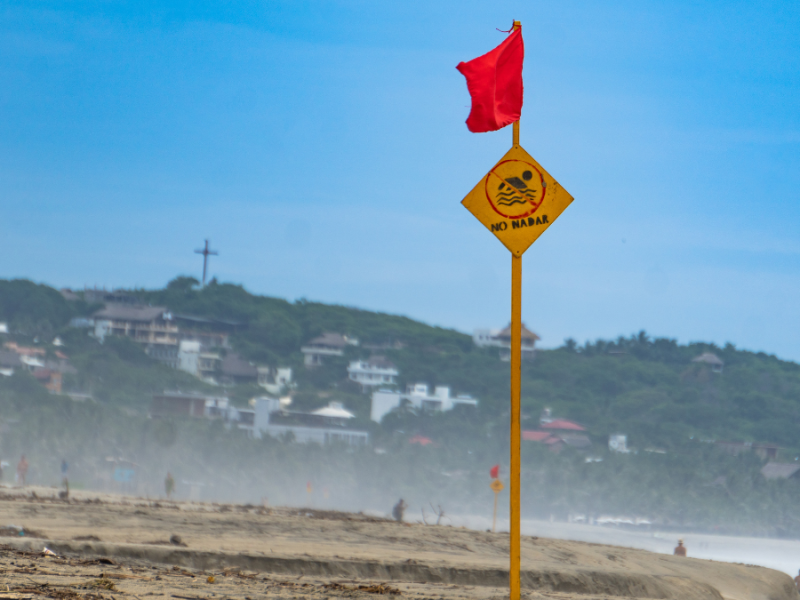 Ein Strand mit einem Schild und einer roten Flagge.