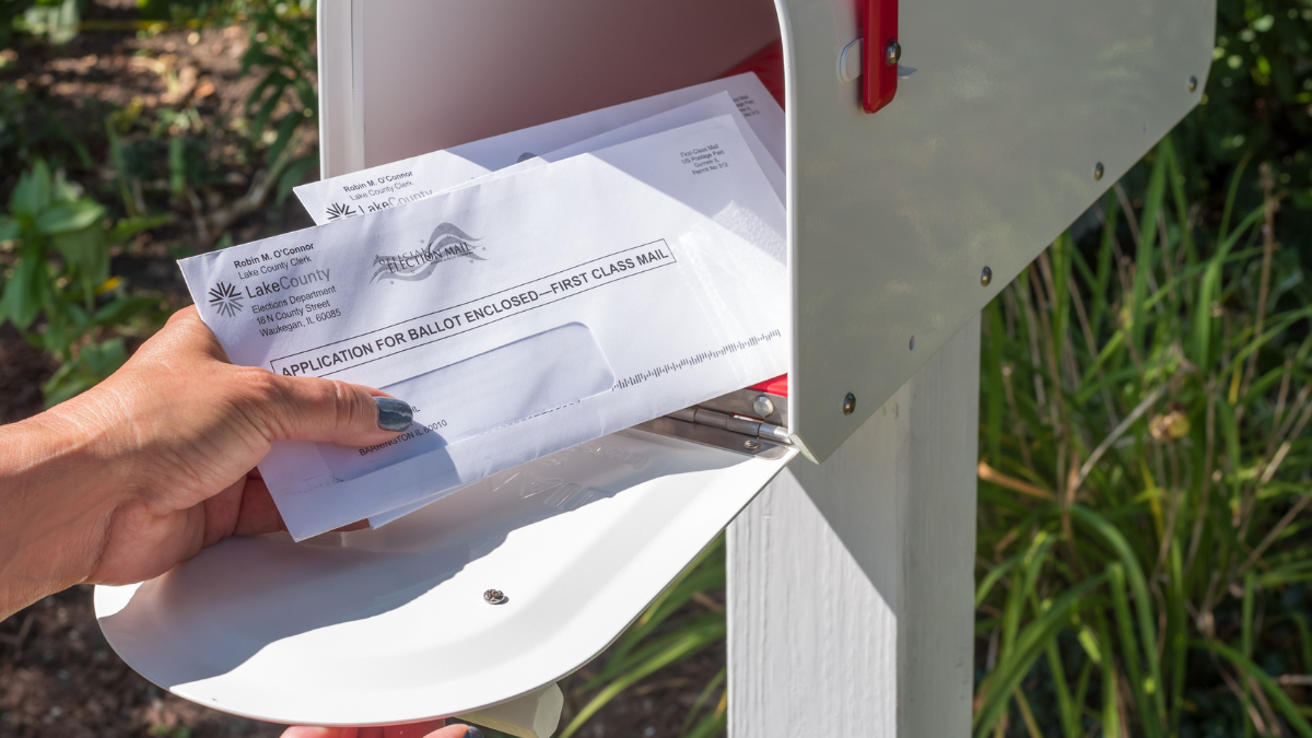 Eine Person holt Post aus dem Briefkasten.