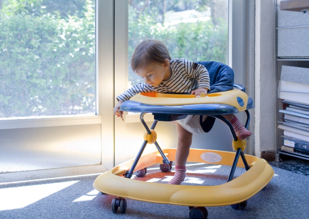 Ein Kleinkind spielt in einem Babywalker, einem sogenannten Gehfrei.