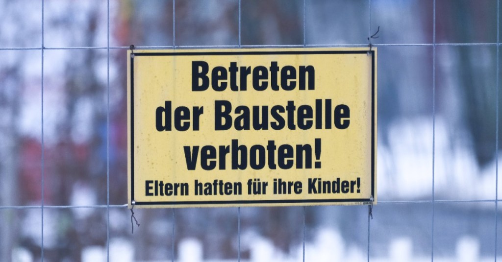 Schild "Eltern haften für ihre Kinder" an einem Baustellenzaun