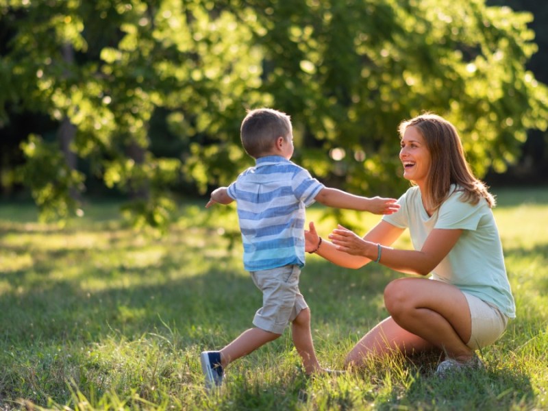 Kleiner Junge rennt im Park auf seine Mutter zu