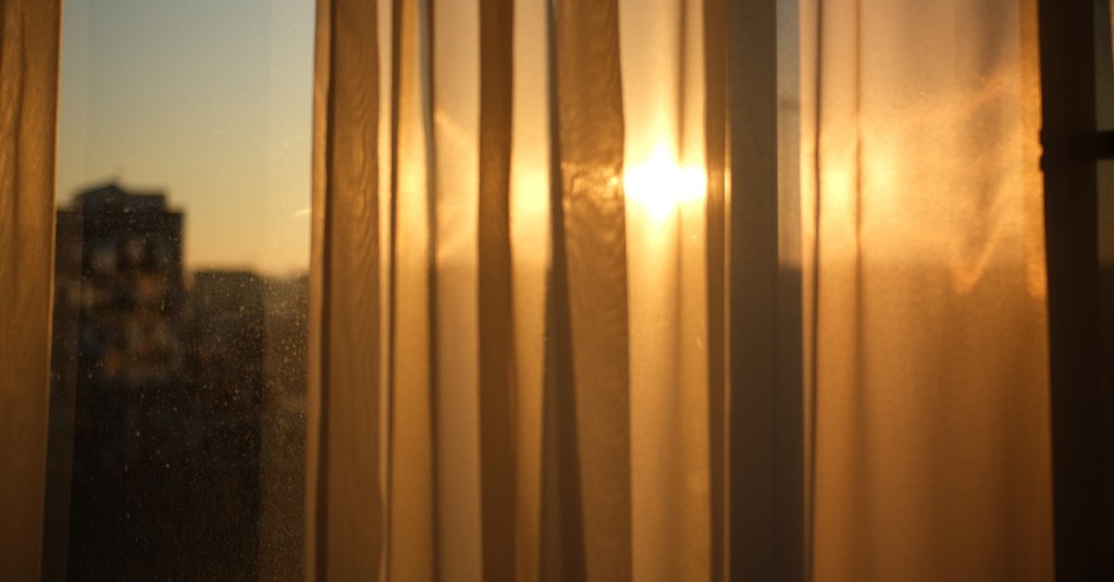 Vorhänge an einem Fenster. Die Sonne scheint durch das Fenster.