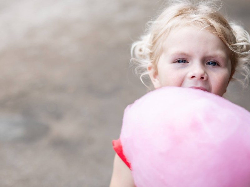 Kleines Mädchen hält pinke Zuckerwatte in den Händen