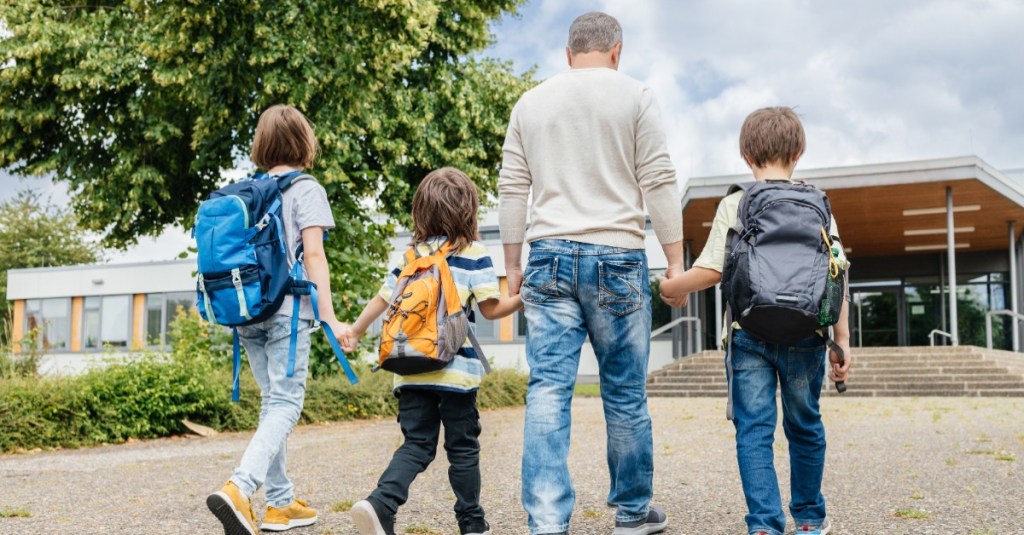 sicherer Schulweg: Vater bringt seine drei Schulkinder in die Schule