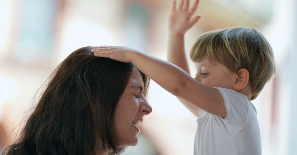 Ein kleiner Junge haut seine Mama auf den Kopf