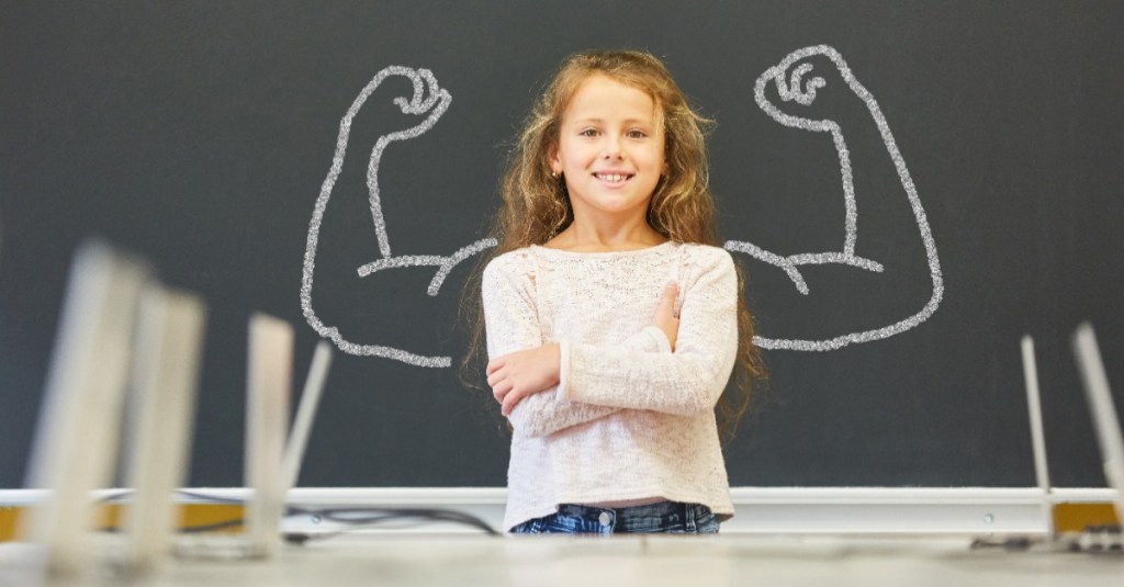 sicherer Schulweg: Mädchen in Schule steht vor Tafel mit Muskeln